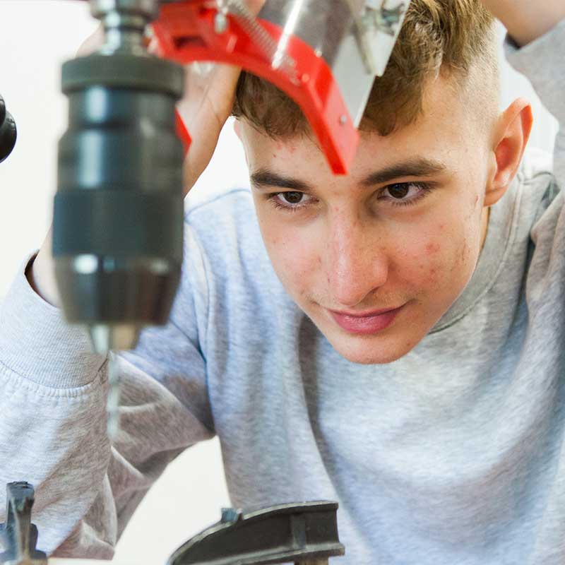 Schueler arbeitet mit einem Bohrer