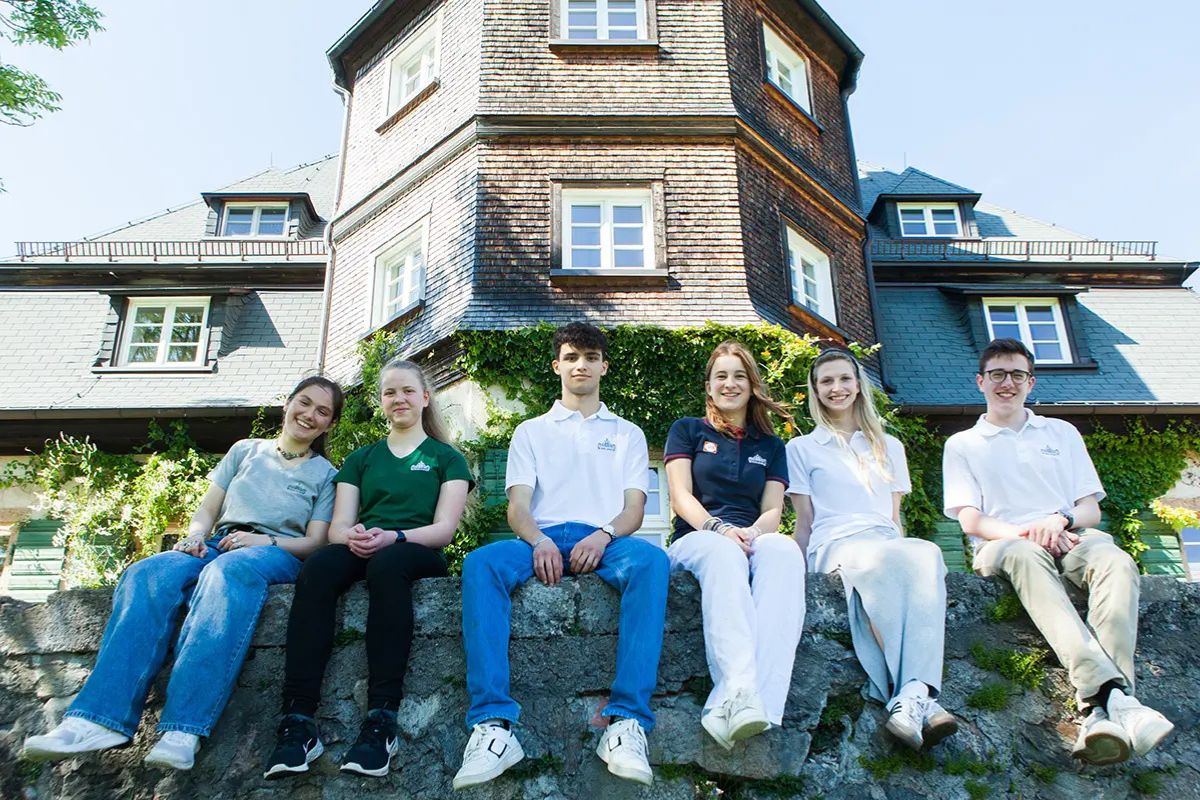 schulheim-internat-birklehof Schüler sitzen auf einer Mauer vor dem Gebäude des Internat Birklehof zum Thema Schulheim: Individuelle Förderung auch außerhalb der Schweiz möglich