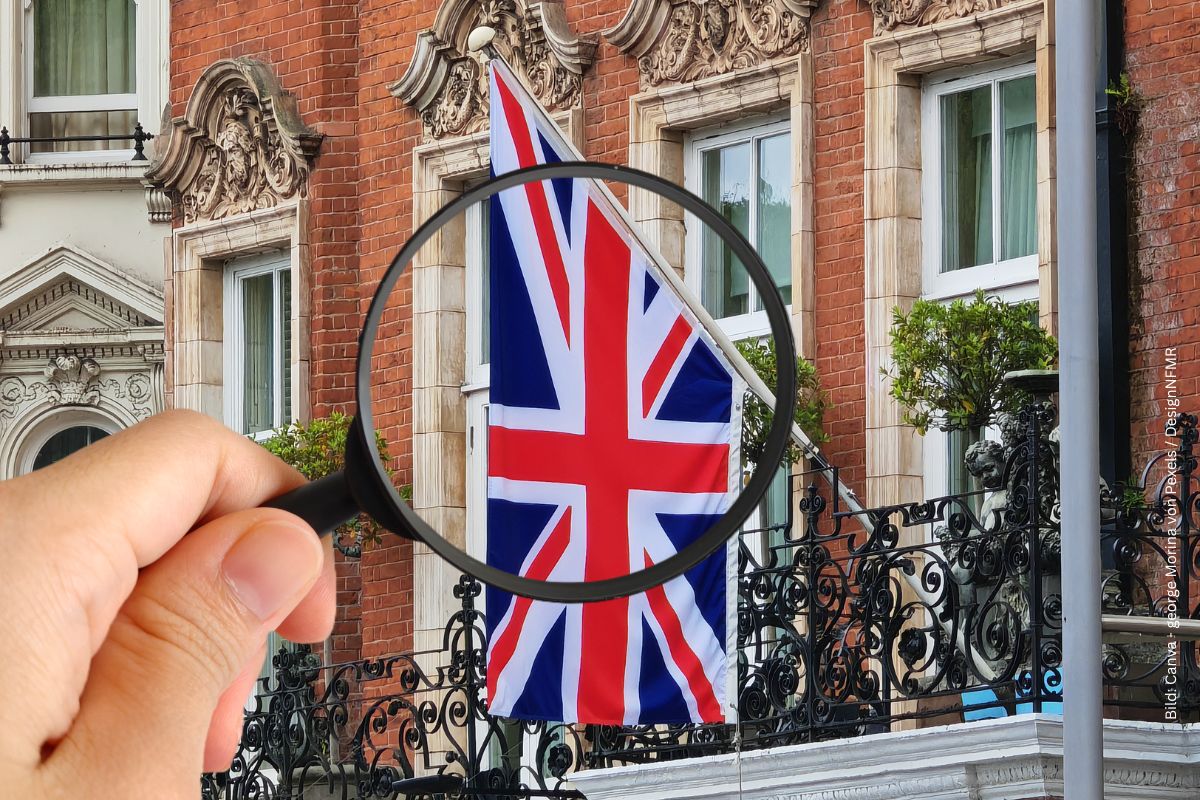 typische englische Gebäudefassade mit Englandflagge. Im Vordergrund eine Hand mit einer Lupe zum Thema Internat in England - Bildung, Tradition und internationale Perspektiven
